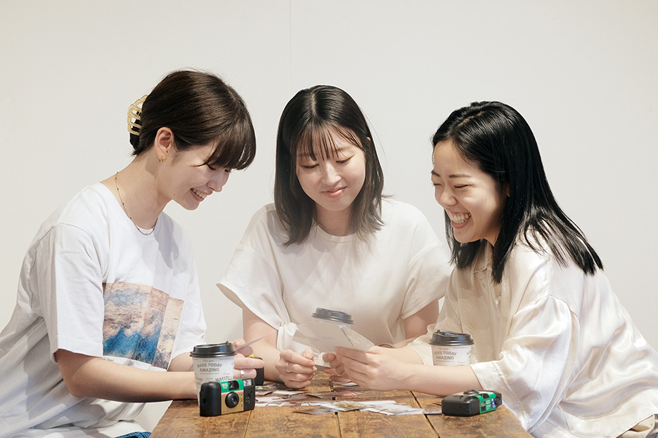 プリントアウトした写真を見ながら談笑している女性3人の写真