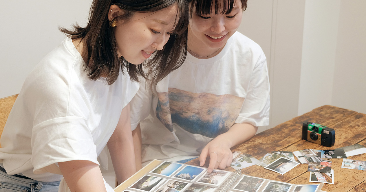 「写ルンです」で撮影した写真をアルバムにまとめている女性2人の写真