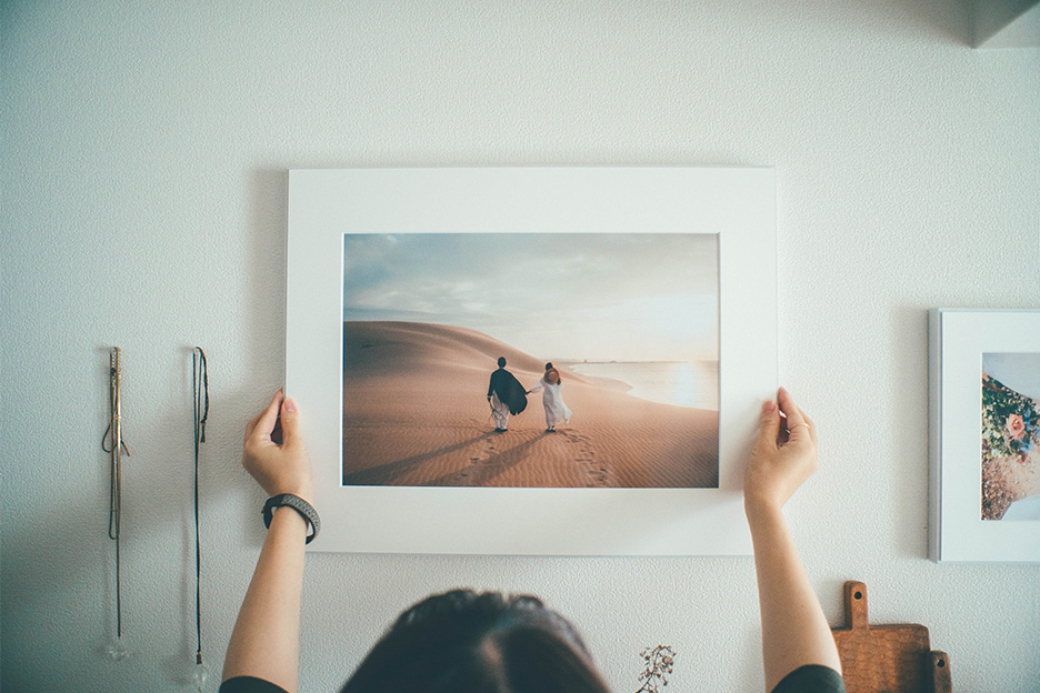 写真がプリントされた「WALL DECOR」を壁に飾ろうとしている写真