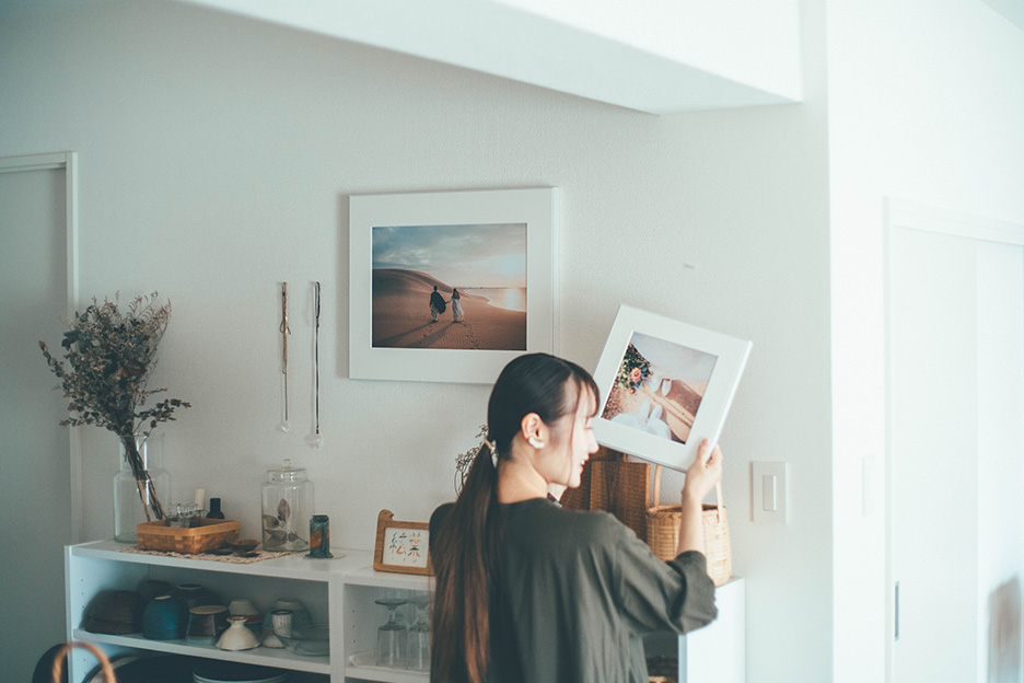 写真がプリントされた「WALL DECOR」を壁に飾ろうとしているmisuzuさんの写真