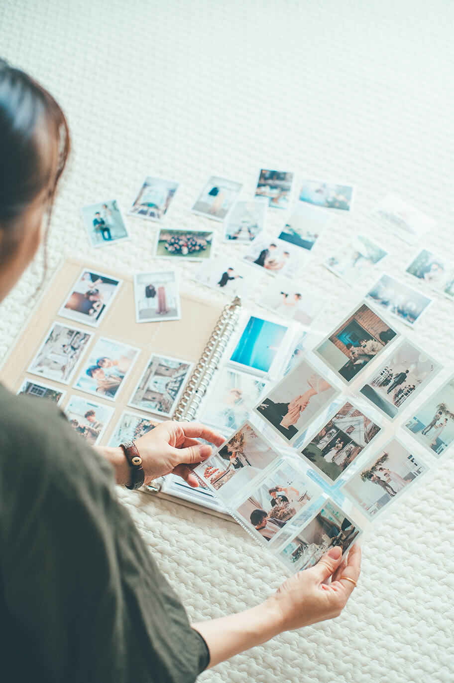 「ハーフサイズプリント」にプリントされた写真をアルバムに入れながら、写真を眺めている女性の写真