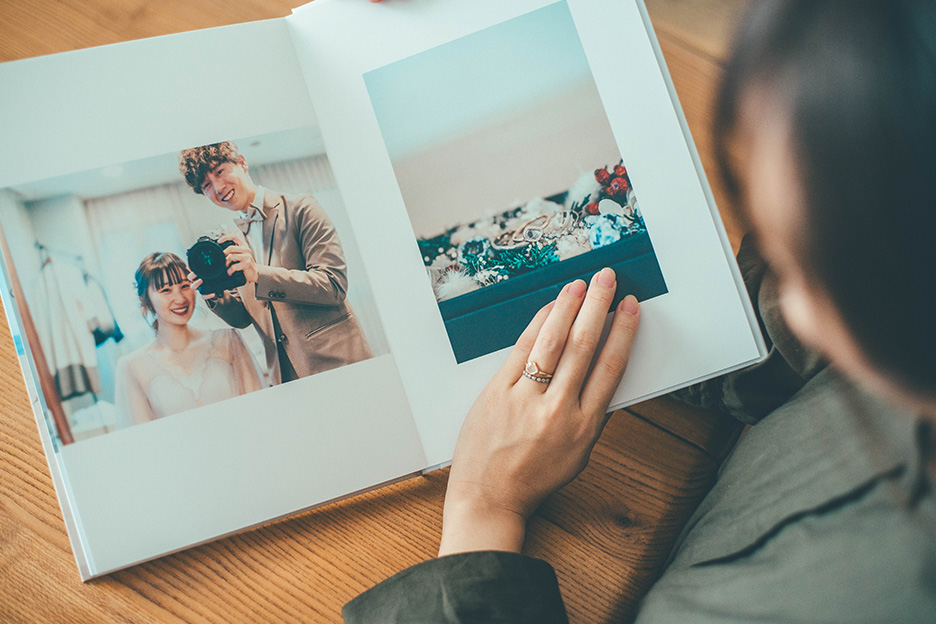 結婚式の写真をプリントした「フォトブック ハードカバー」を、薬指に指輪をつけた手で開く写真