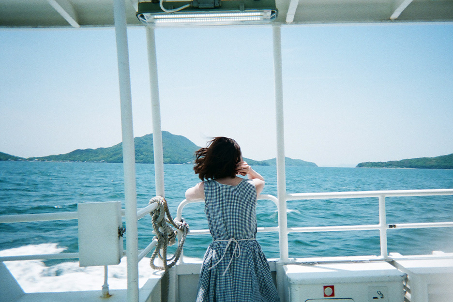 船に乗って海を眺める女性のうしろ姿の写真