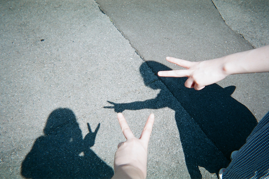 地面に映る、ピースする2人の影の写真