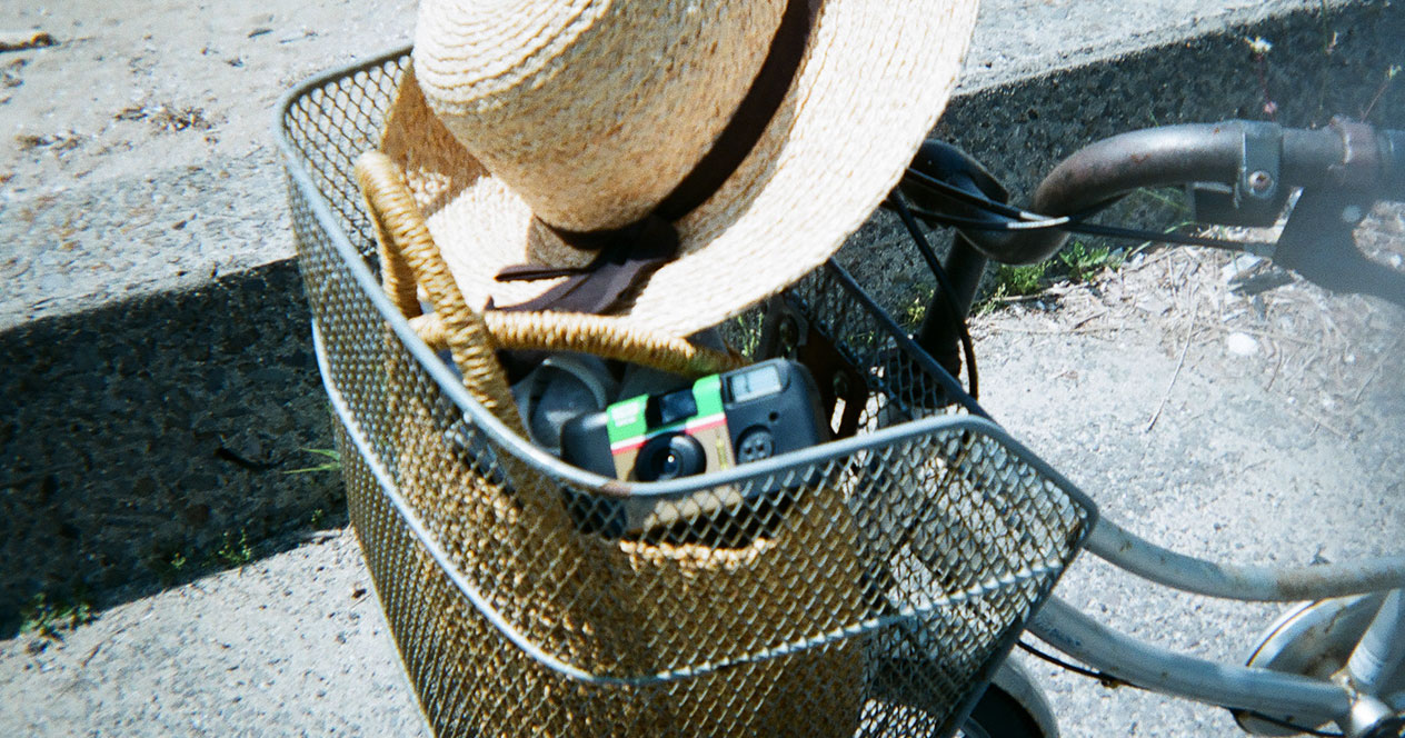 自転車のカゴに、麦わら帽子とカゴバッグと「写ルンです」が入った写真