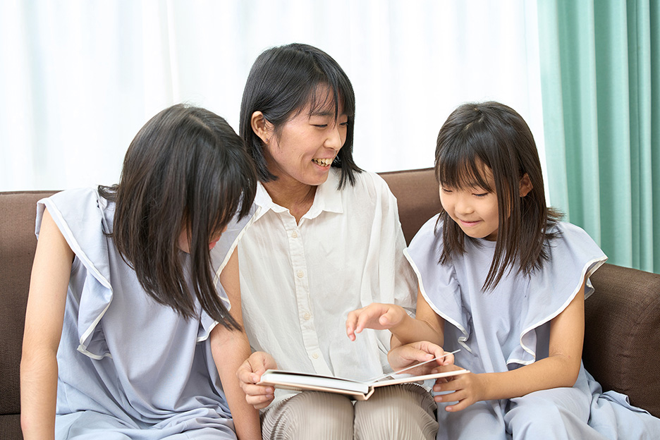 小野寺さんと2人のお子さんがソファーに座って、イヤーアルバムを見ながら談笑している写真