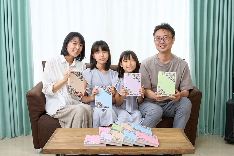 イヤーアルバムを持っている、小野寺さんご家族4人の写真