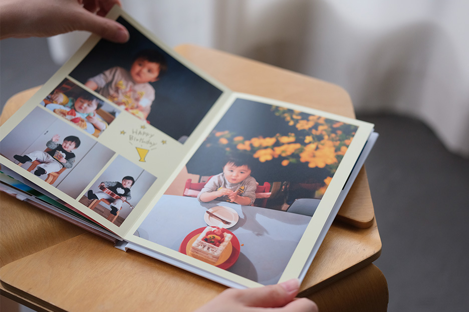 子どもが掲載されたハードカバーのアルバムを開いている写真