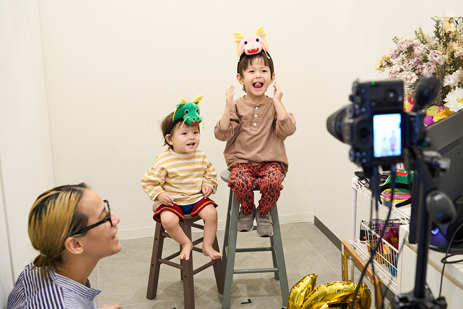 笑顔で撮影する子ども2人とそれを見守る母親の写真