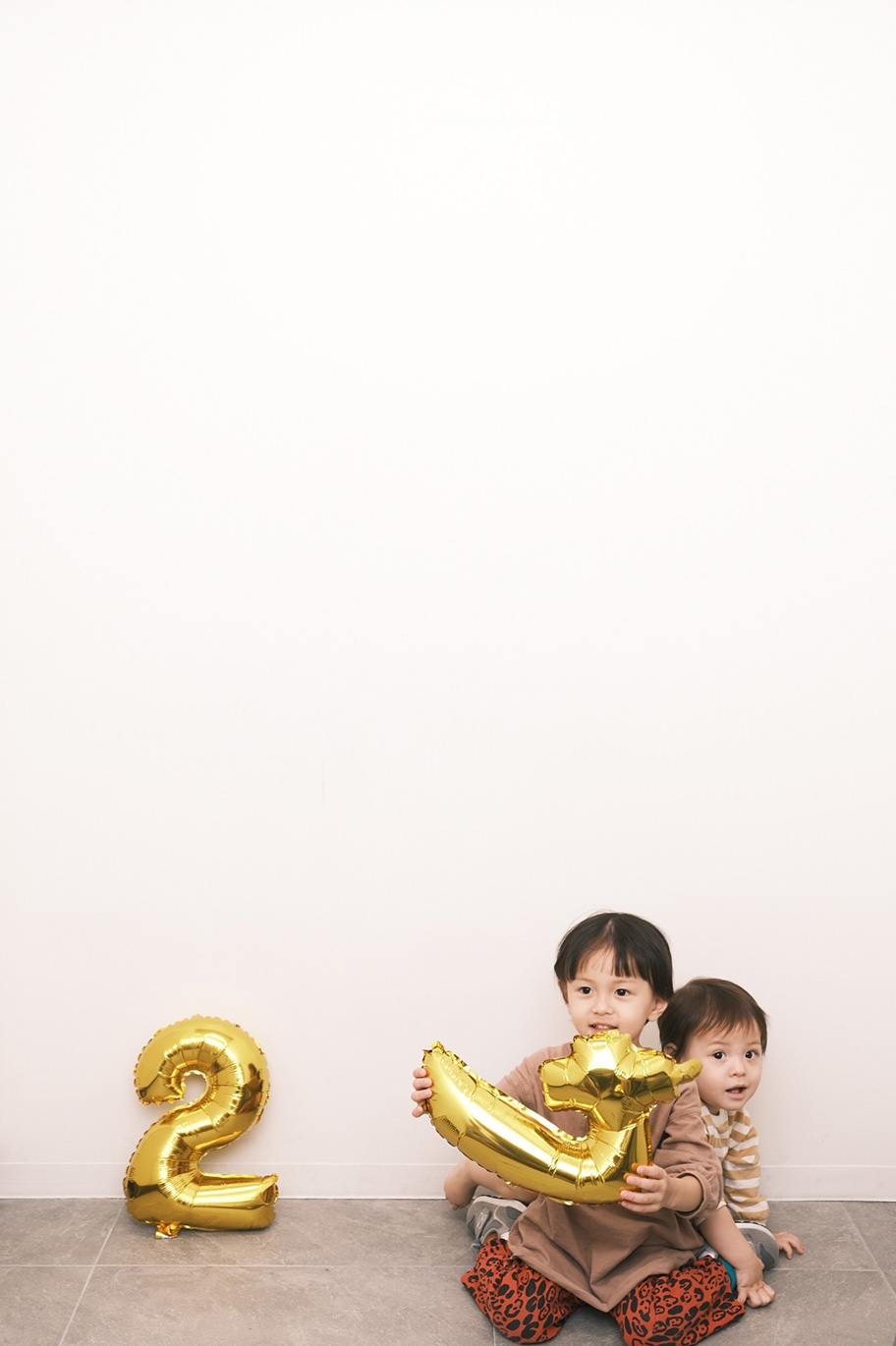 上部に余白を残して撮影した、子ども2人が風船を持って遊んでいる写真