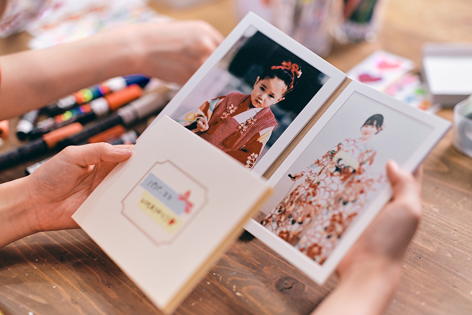 メッセージが書かれたフォトフィーユの表紙と幼いころの写真と振袖姿の写真がプリントされた中面の写真