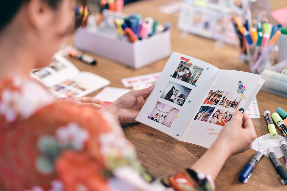女性が思い出の写真がプリントされたPhotoZINEを見ている写真