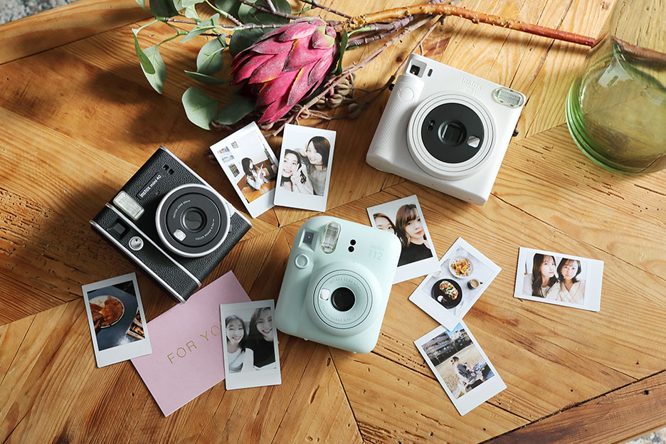 “チェキ” INSTAX mini 12と“チェキ” INSTAX mini 40と“チェキ” INSTAX SQUARE SQ1とチェキプリントがランダムに置いてある写真