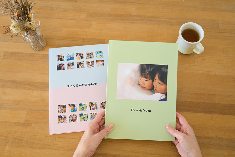 保育園や幼稚園の写真がプリントされたイヤーアルバムの表紙と、家庭で撮影した写真をプリントしたイヤーアルバムの表紙の写真