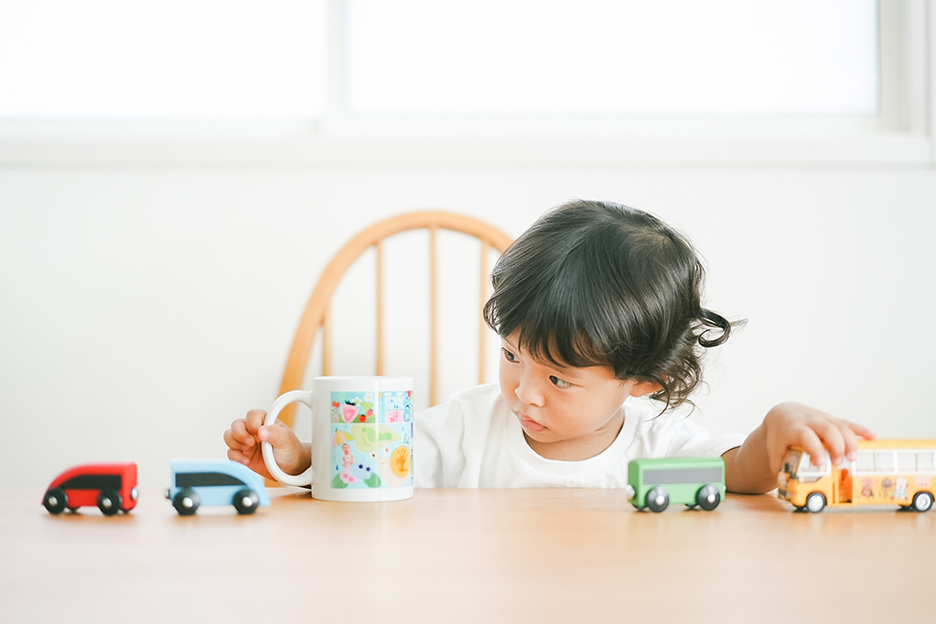 子どもの作品の写真をプリントした写真入りオリジナルマグカップと、それを見つめる子どもの写真